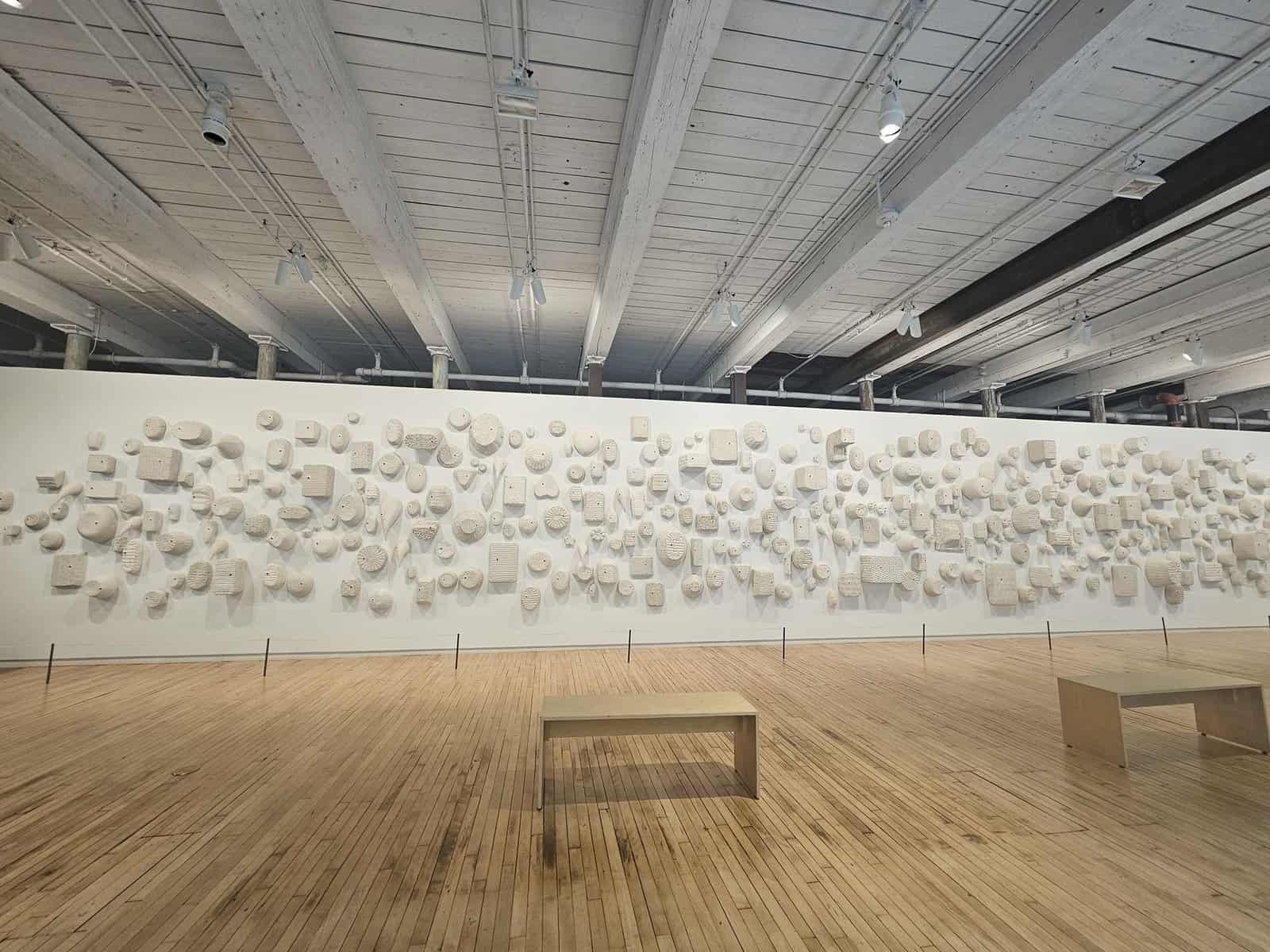 Mass moca: a weekend inside massachusetts' wildest art museum 14 » 2026 » roaming sparrow A wall of ceramic faces with blinking eyes in woven baskets at Mass MoCA