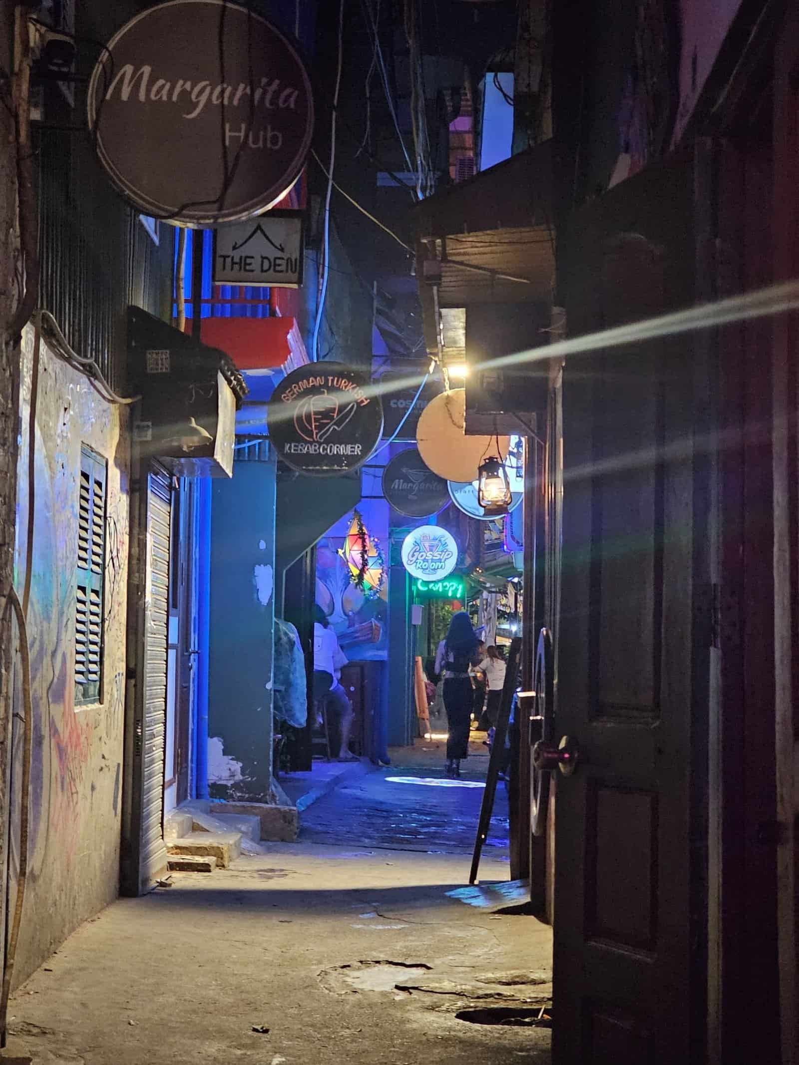 Phnom penh on foot: bassac lane, the riverside, and a day of wandering 24 » 2026 » roaming sparrow A grungy neon-lit back alley off Bassac Lane in Phnom Penh at night