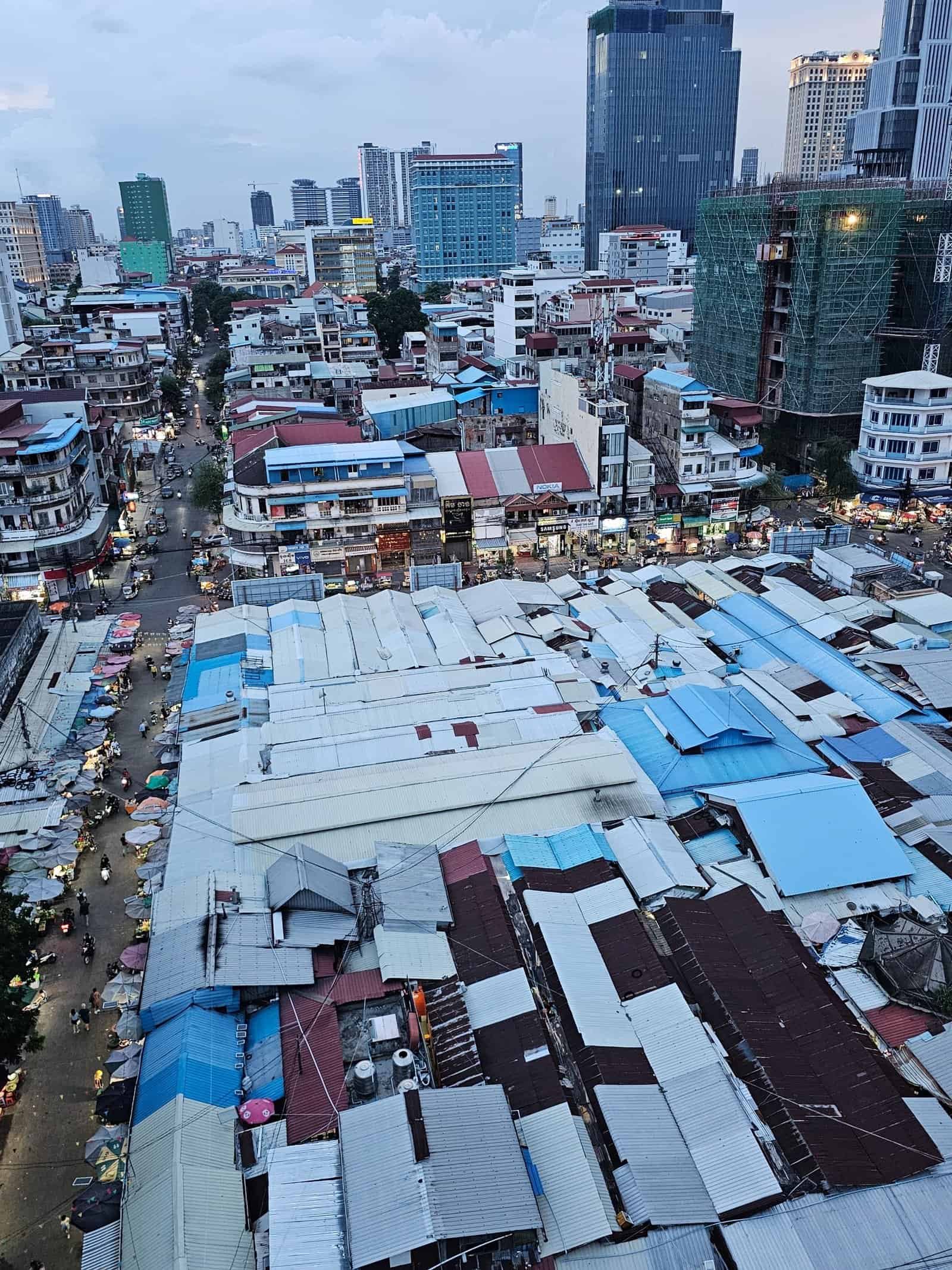 Phnom penh on foot: bassac lane, the riverside, and a day of wandering 29 » 2026 » roaming sparrow A rooftop view over Phnom Penh's patchwork market roofs and high-rises