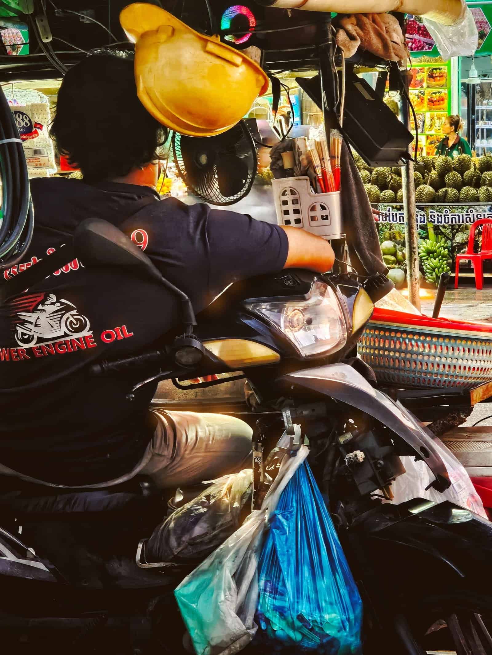 A street vendor on a motorbike under a yellow lamp on a Siem Reap night walk