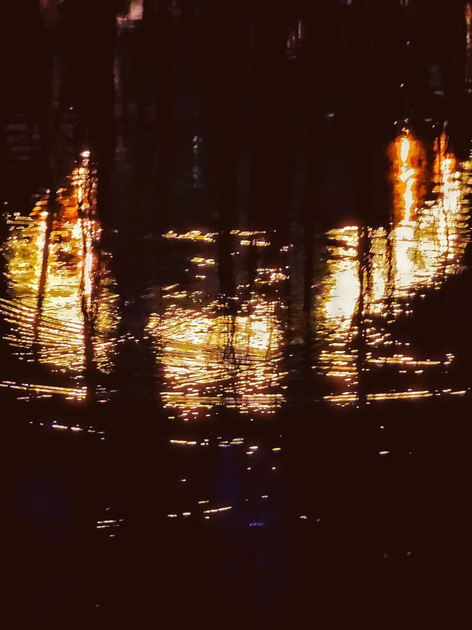 Hanging woven rattan lanterns reflected in water on the Siem Reap riverside