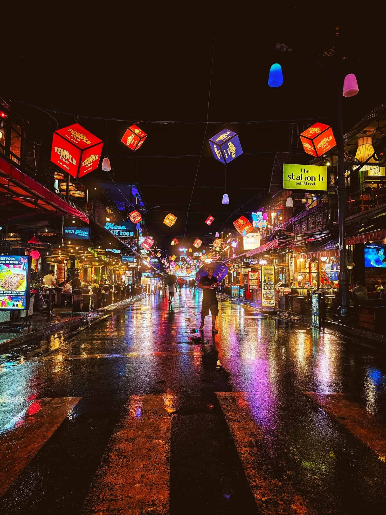 Hanging cube lanterns glowing over a wet Siem Reap crosswalk at night